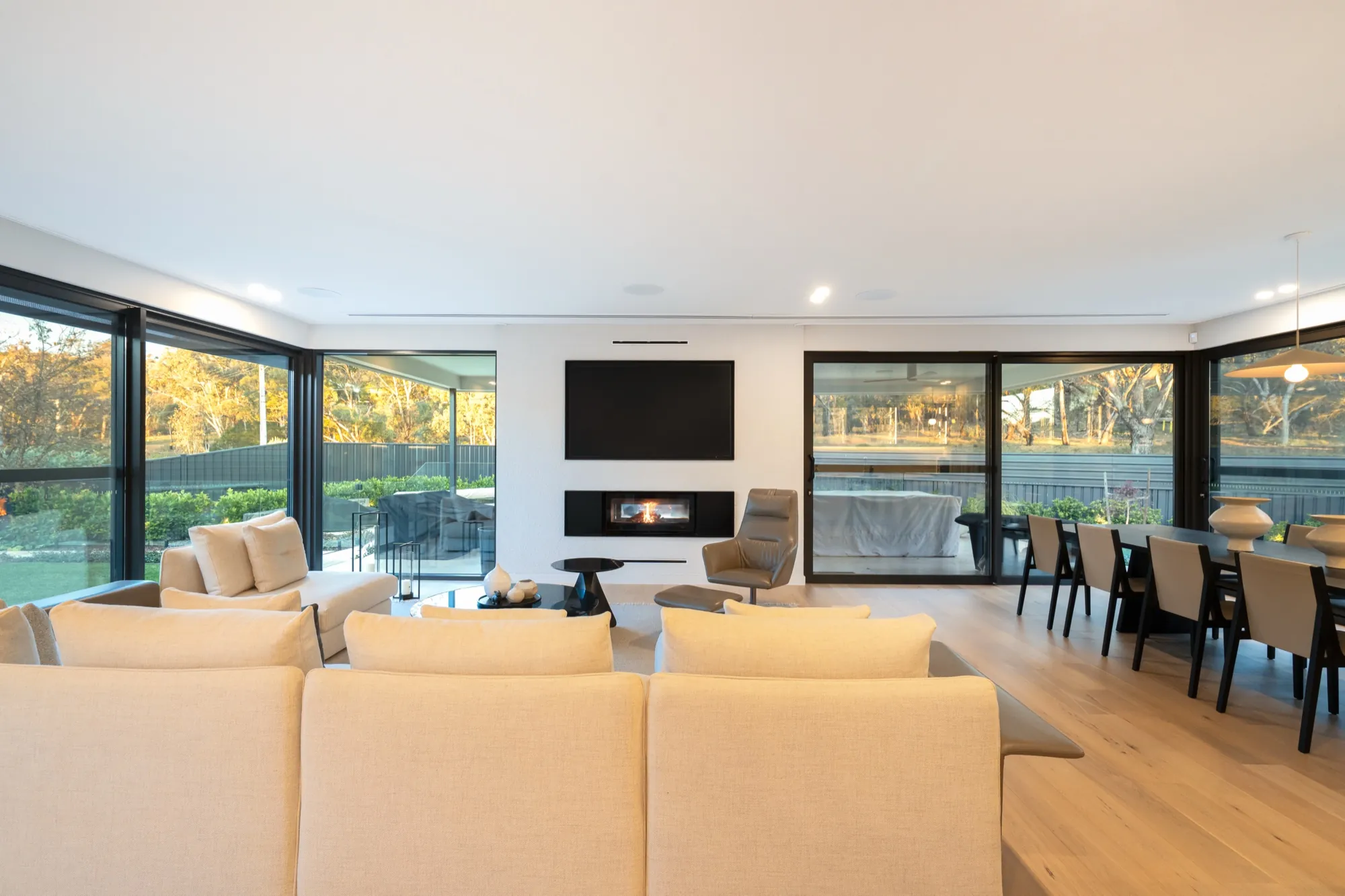 Living and dining area at the Hackett new build with fireplace, wall-mounted TV and layered lighting