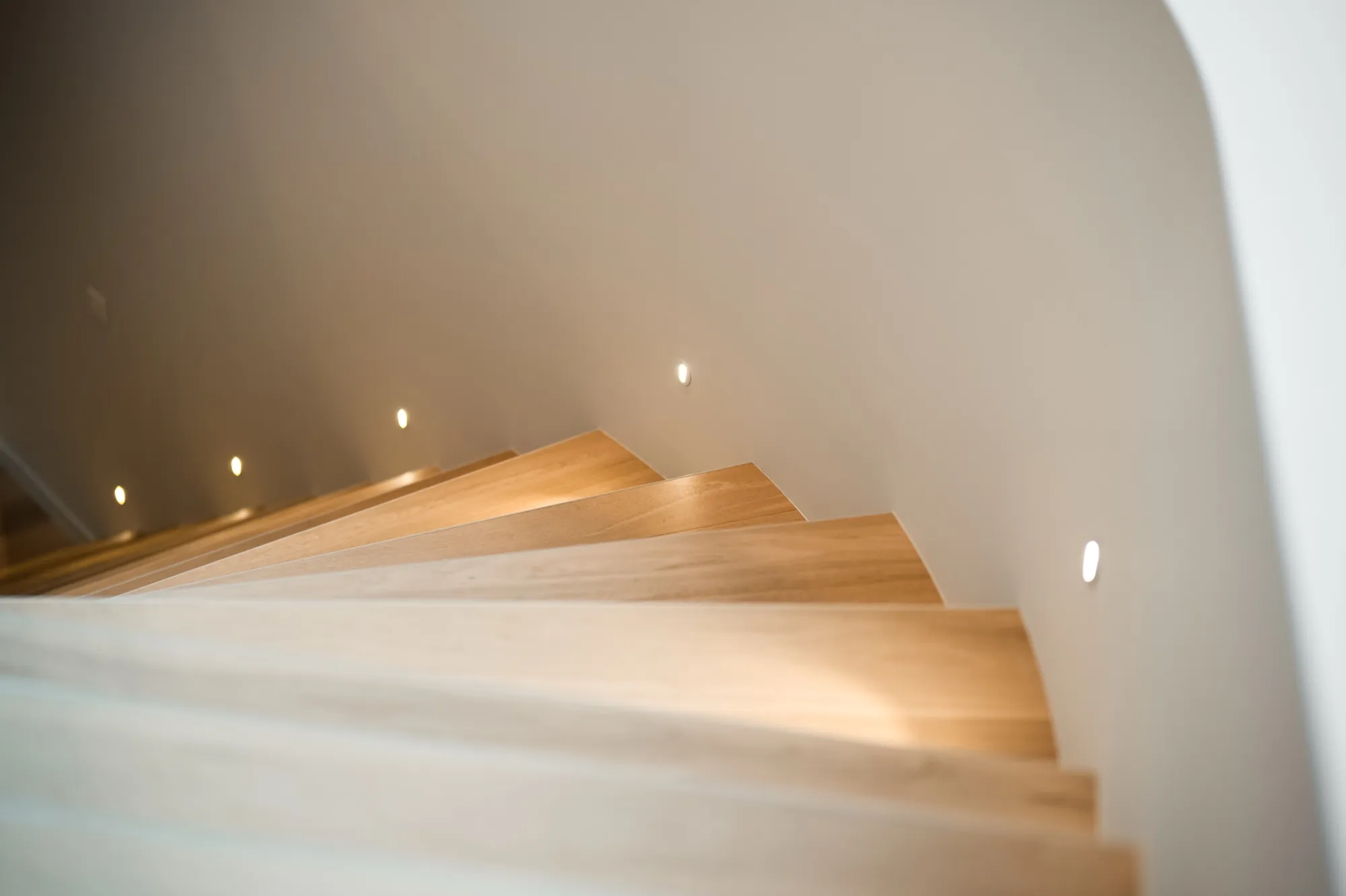 Recessed wall lights washing light across the timber stairs at the Hackett new build