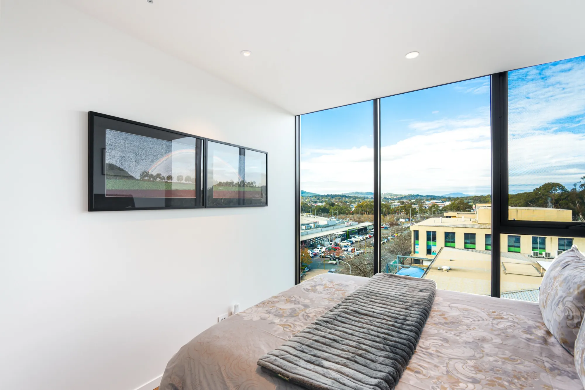Bedroom in the first Phillip apartment with picture lighting and city views