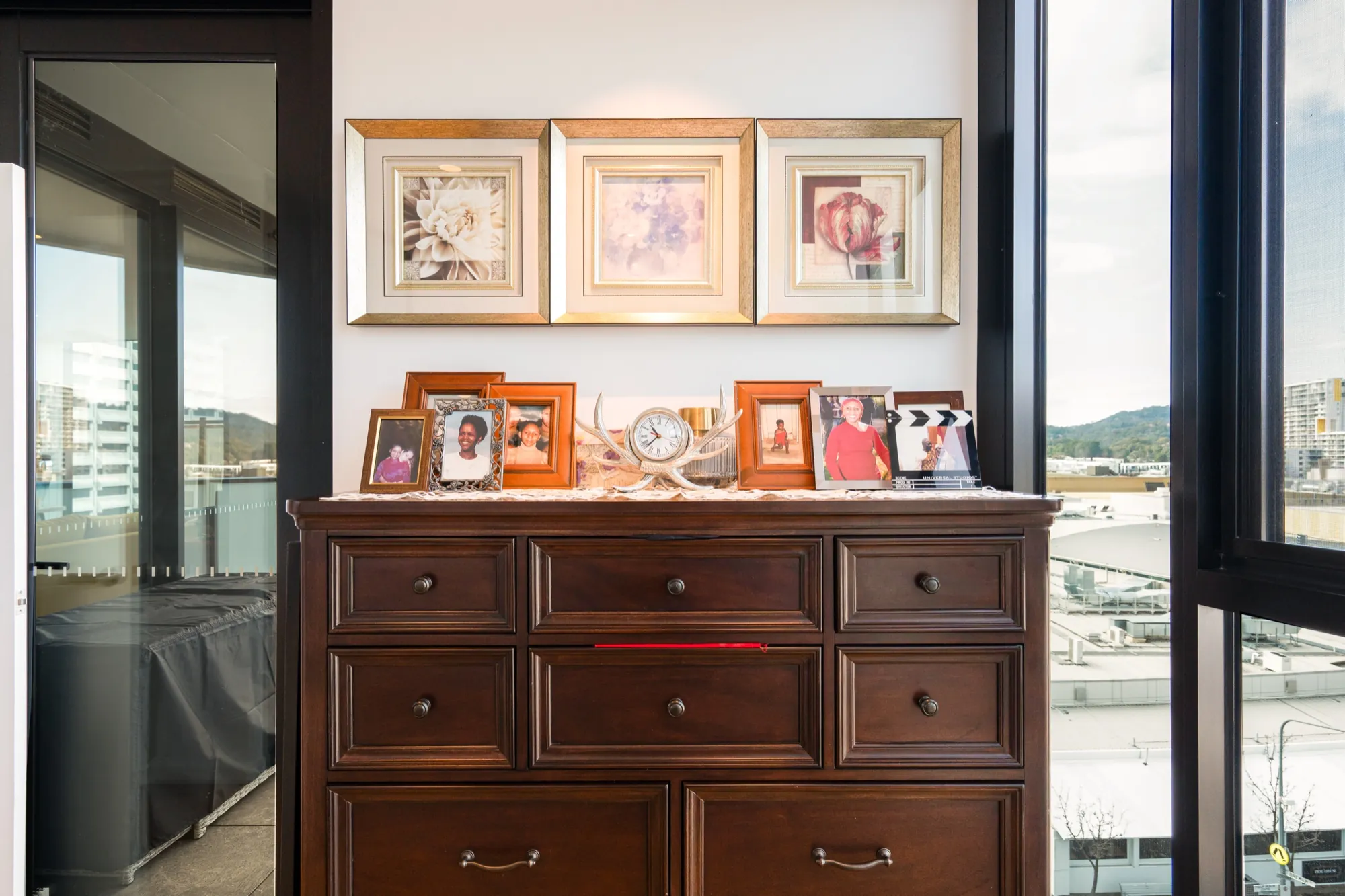 Timber dresser and framed family photos lit softly in the first Phillip apartment