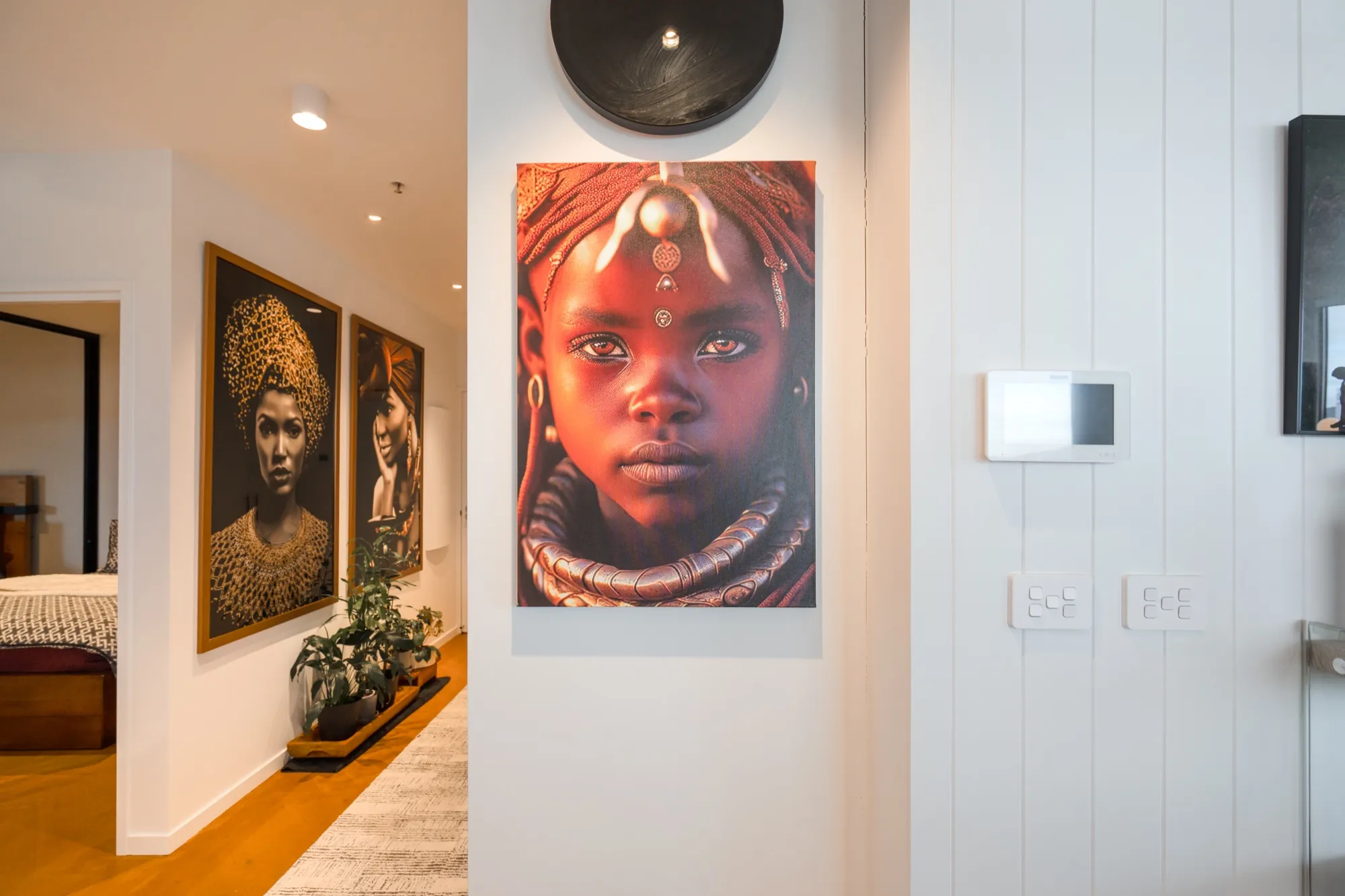 Hallway gallery wall in the first Phillip apartment with portrait artwork picked out by the lighting