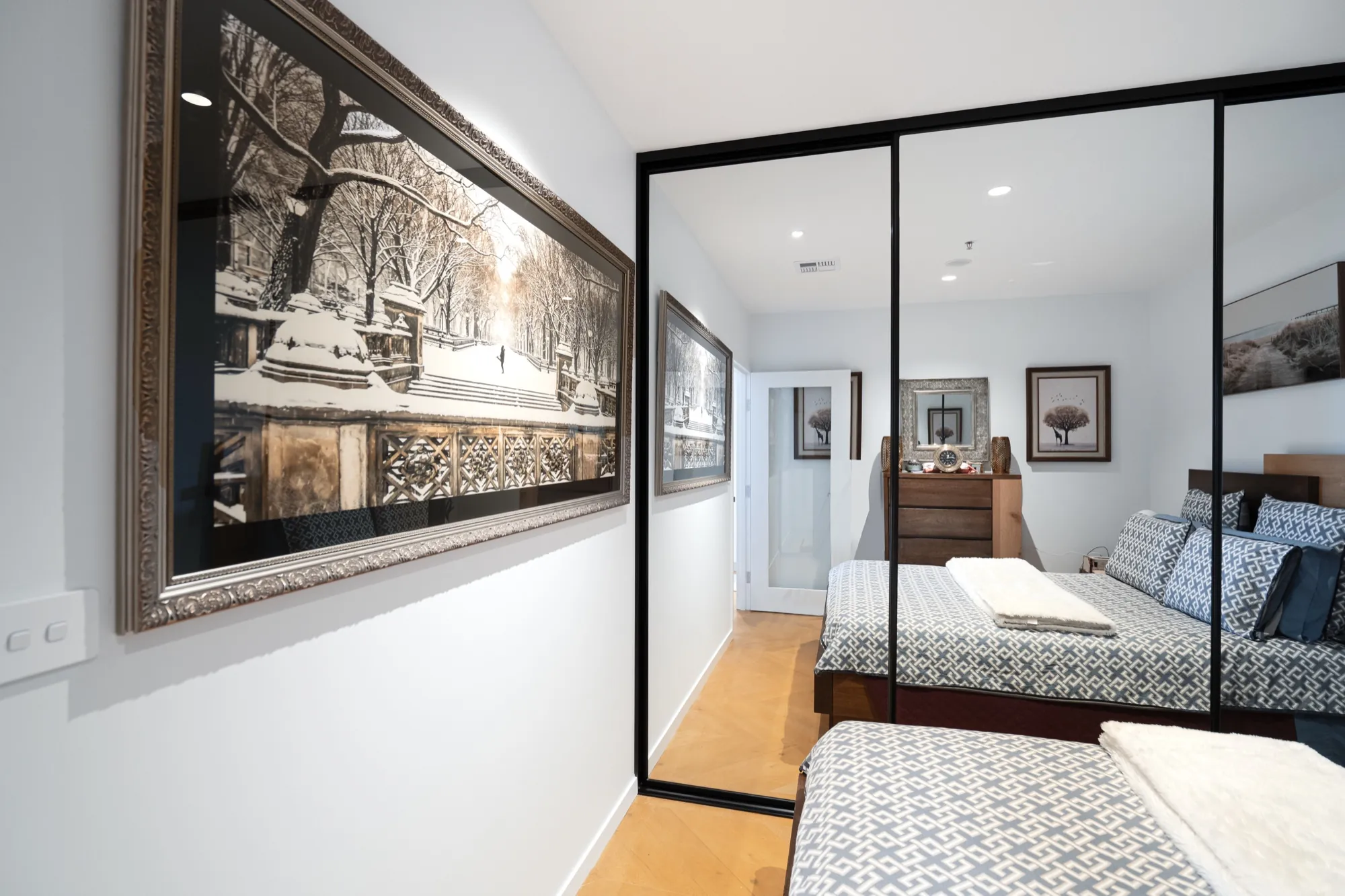 Bedroom with mirrored wardrobes and framed prints in the first Phillip apartment
