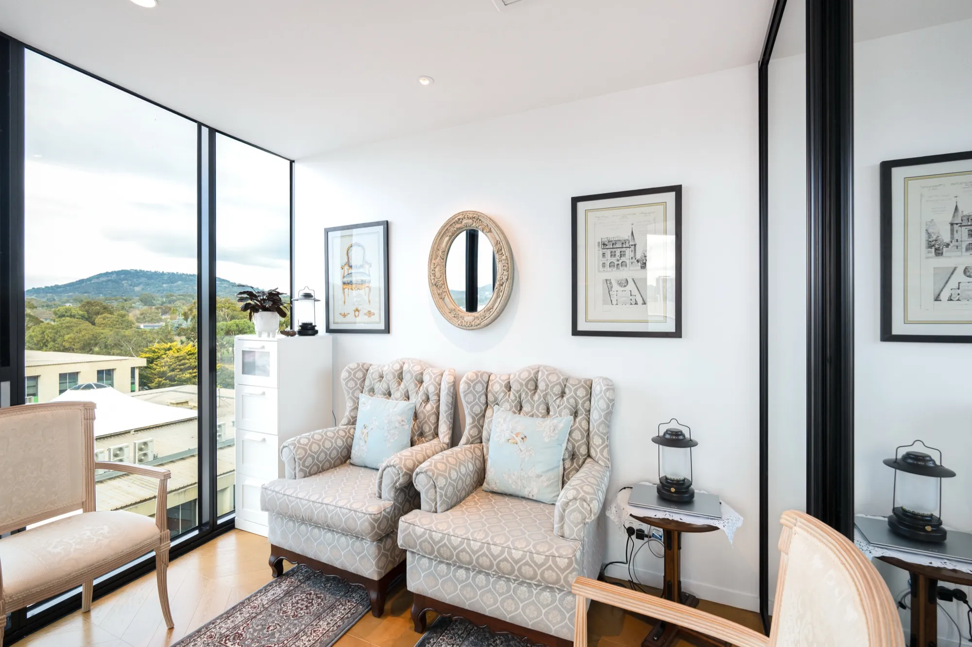 Reading corner with armchairs and a round mirror in the first Phillip apartment