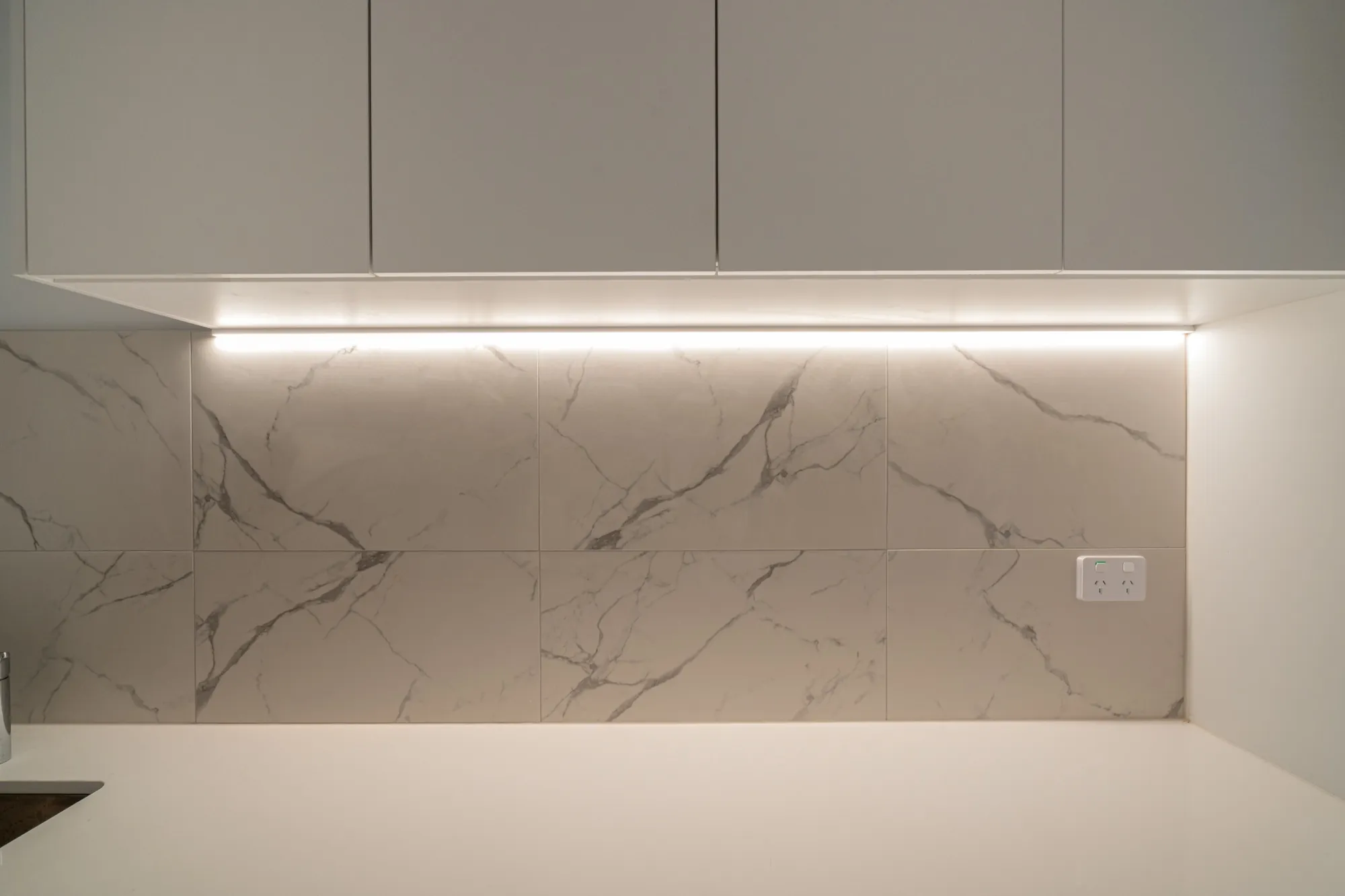 Marble splashback in the second Phillip apartment lit by a continuous under-cabinet LED strip